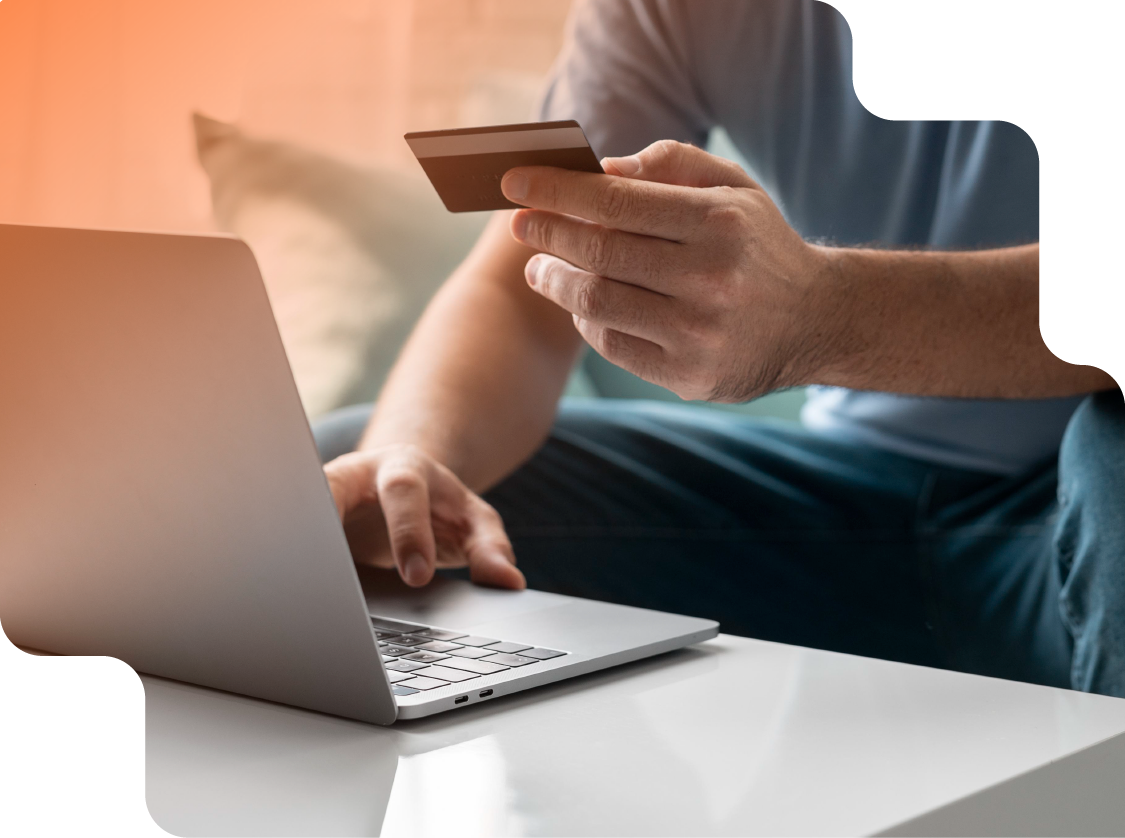 Imagen de una persona con una computadora y la tarjeta de credito en la mano